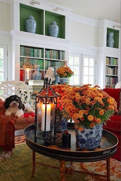 a dog sitting on a couch in a living room next to a table with flowers and candles