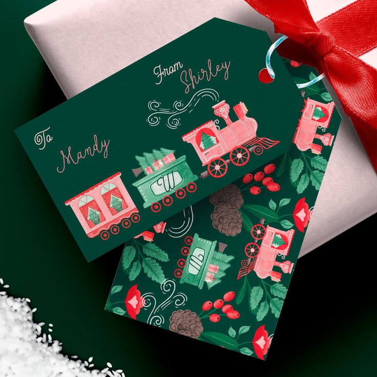 two christmas cards sitting next to each other on top of a green background with red ribbon