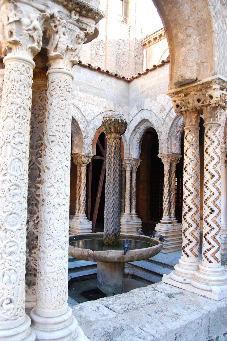 an outdoor fountain surrounded by pillars and arches