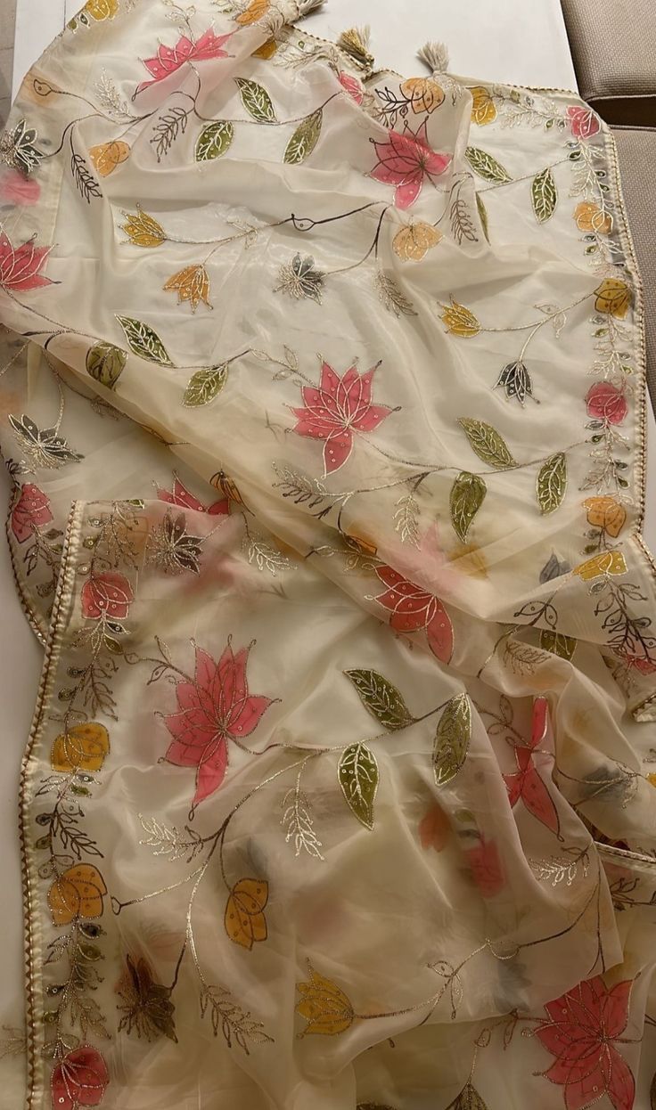 a white table cloth with flowers and leaves on it sitting on top of a counter