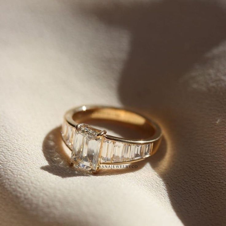 two gold wedding rings sitting on top of a white sheet with shadows from the sun