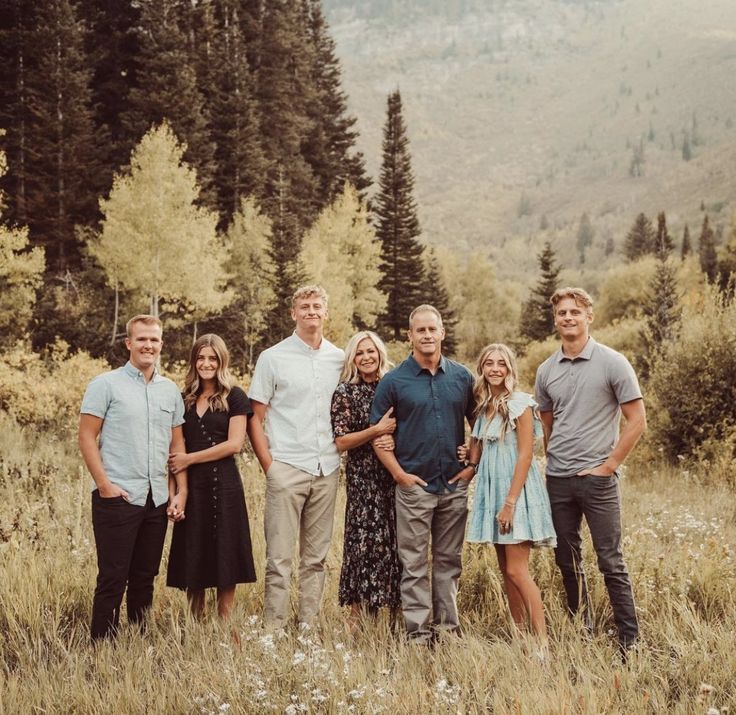 a group of people standing next to each other in a field with tall grass and trees