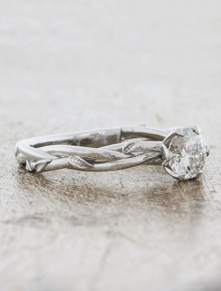 a white gold engagement ring with a twisted band and a round diamond in the center