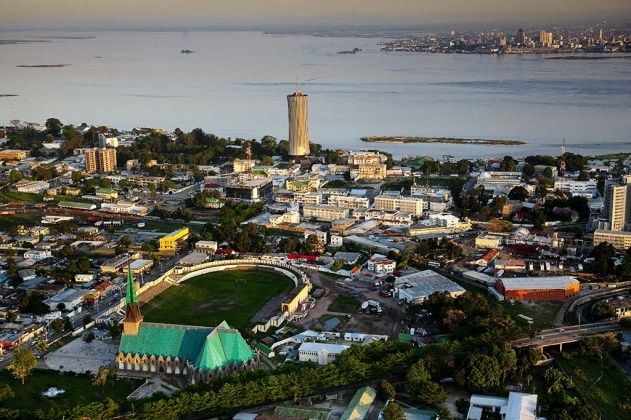 an aerial view of a city with water and buildings in the foreground, including a soccer field