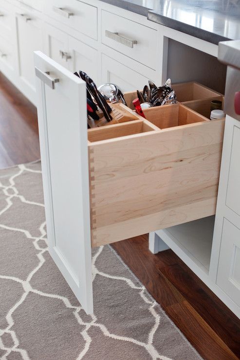 an open drawer in a kitchen with utensils and other items inside the drawers