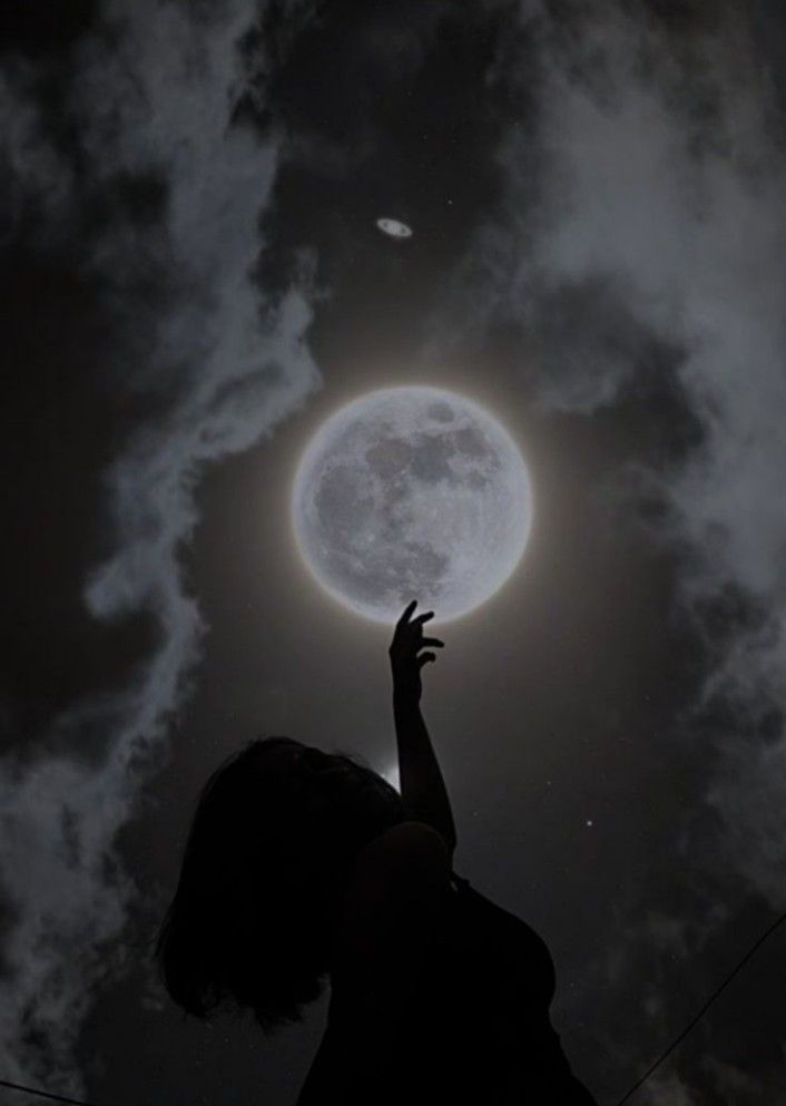 a person reaching up into the sky at night with their hand in the air, under a full moon