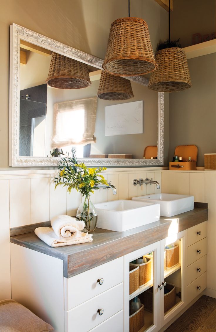 a bathroom with two sinks and baskets hanging from the ceiling over it's mirror