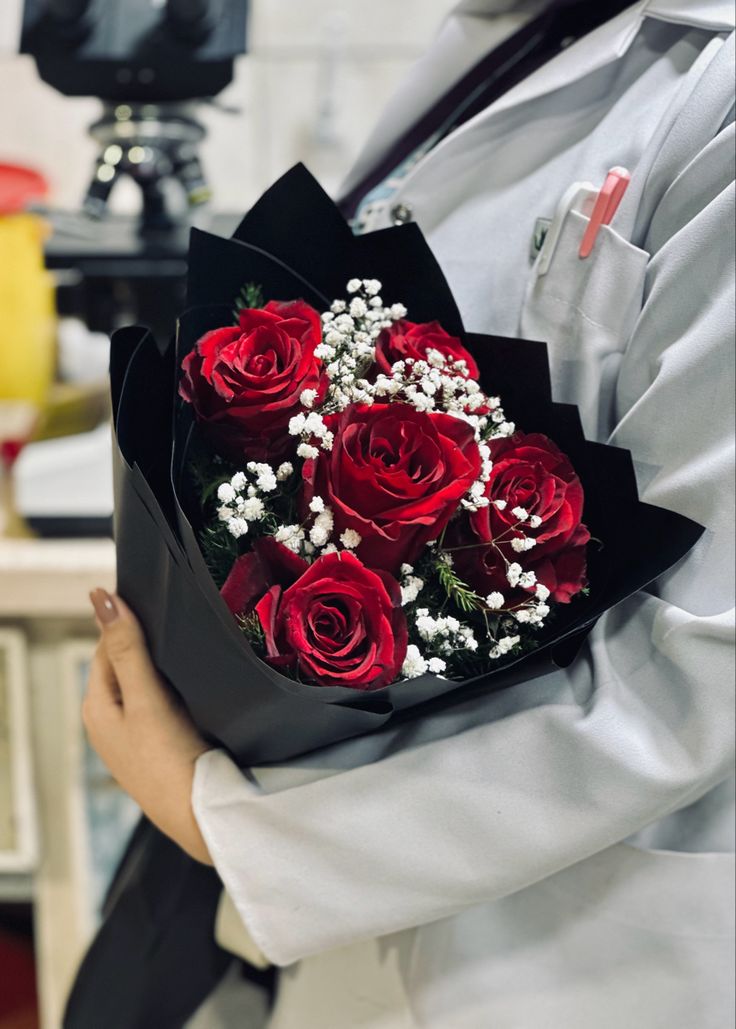 a person holding a bouquet of red roses