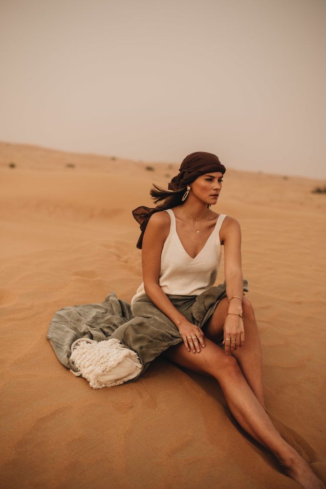 a woman sitting on top of a sandy beach