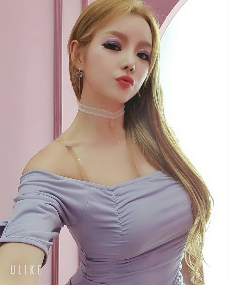 a woman with long blonde hair wearing a purple dress and choker posing in front of a mirror