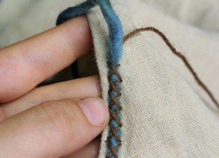 someone is stitching something on the side of a piece of cloth with blue thread