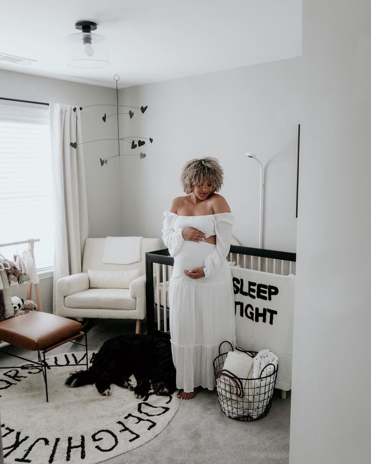 a woman in a white dress standing next to a baby crib