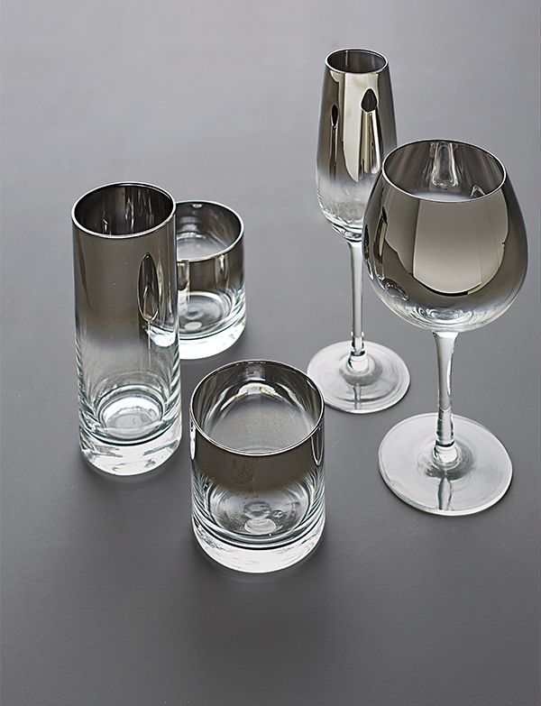 three wine glasses and one empty glass on a gray table with silver rimmed cups