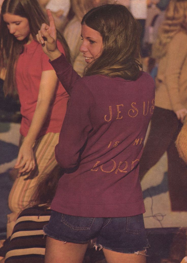 two young women standing next to each other in front of a group of people wearing red shirts