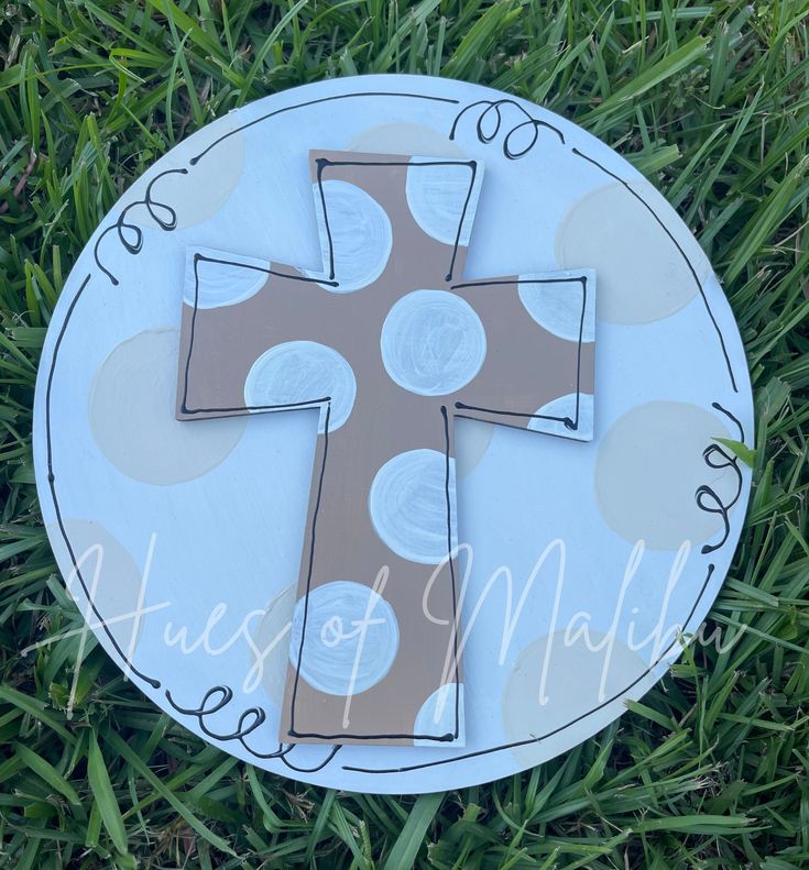 a paper plate with a cross painted on it in the middle of some green grass