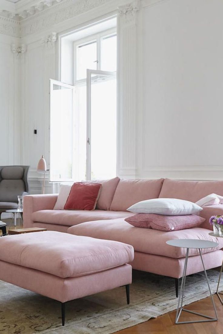 a living room with a pink couch and ottoman