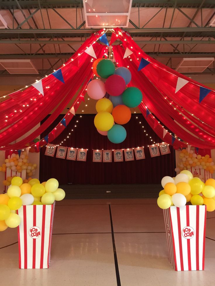 balloons and streamers fill the ceiling in this circus themed birthday party setting, complete with popcorn buckets