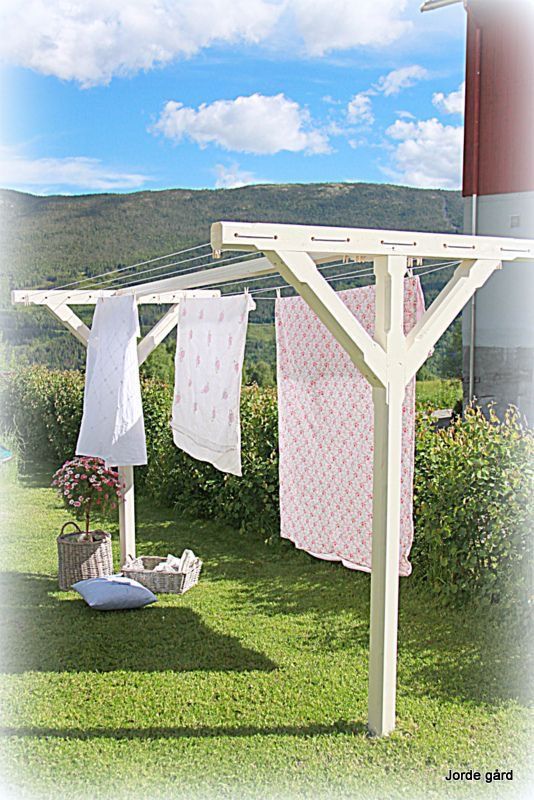 clothes hanging out to dry in the sun on a clothesline near some bushes and flowers