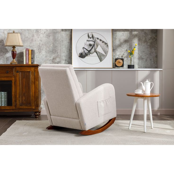 a white rocking chair sitting on top of a rug next to a table and lamp