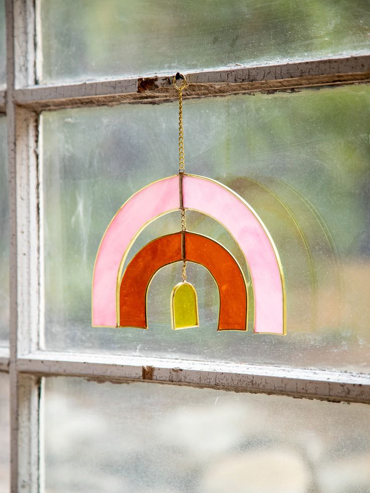 a close up of a stained glass window with a rainbow decoration hanging from it's side