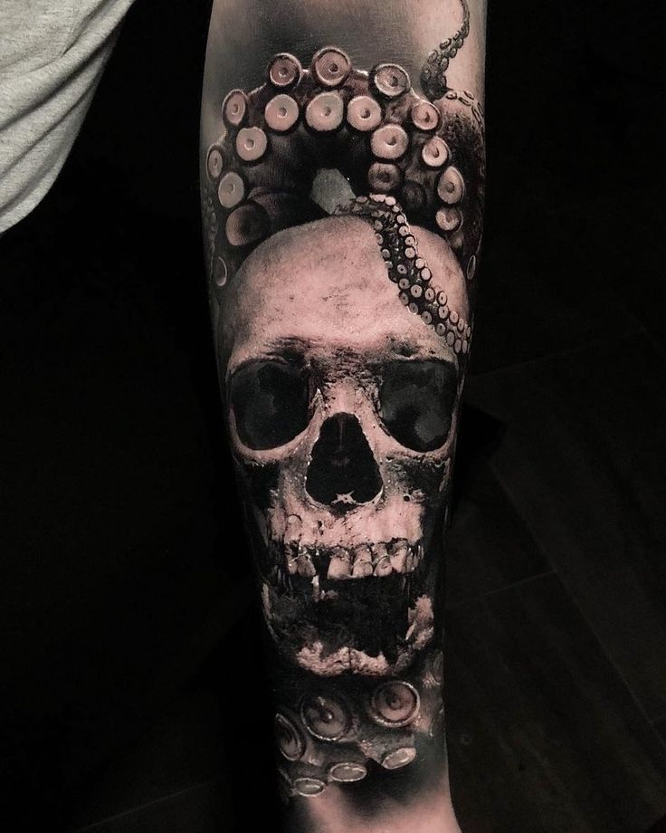 a man's arm with a skull and octopus tattoo on the left side of his leg