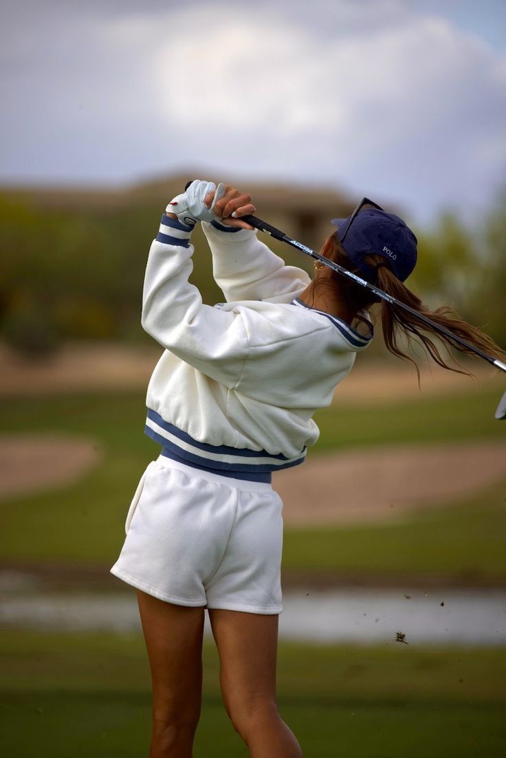 a woman swinging a golf club at a ball