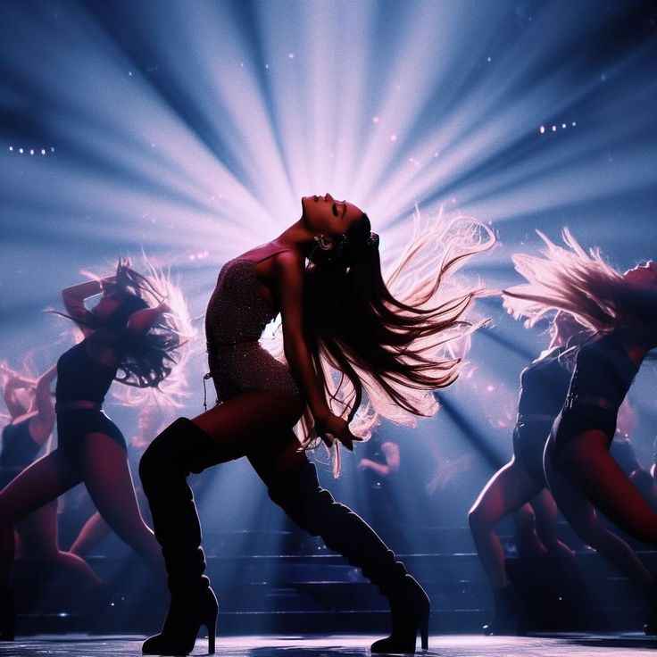 a woman dancing on stage with her hair blowing in the wind and lights behind her