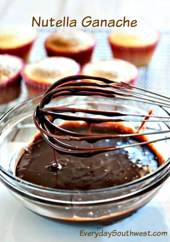 chocolate cupcake batter being whisked in a bowl with other muffins behind it