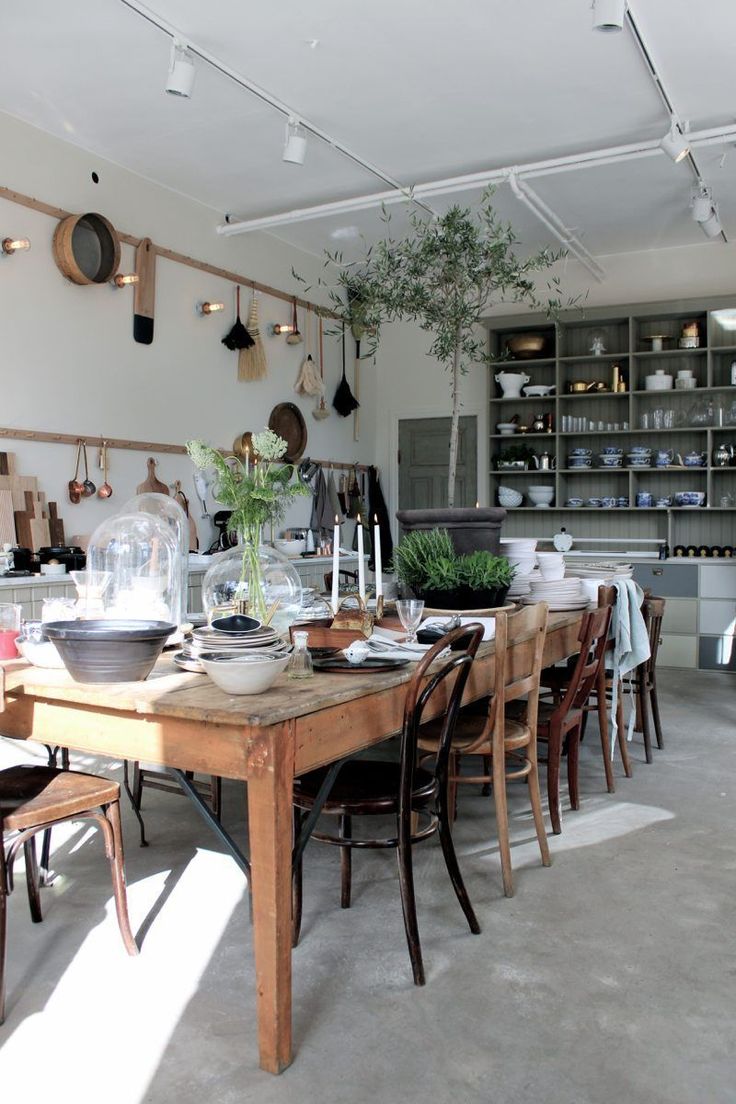 a wooden table surrounded by chairs in a room with lots of shelves and pots on the wall