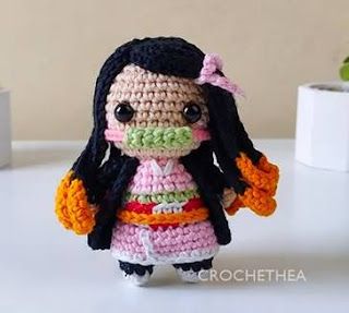 a crocheted doll is standing on a table