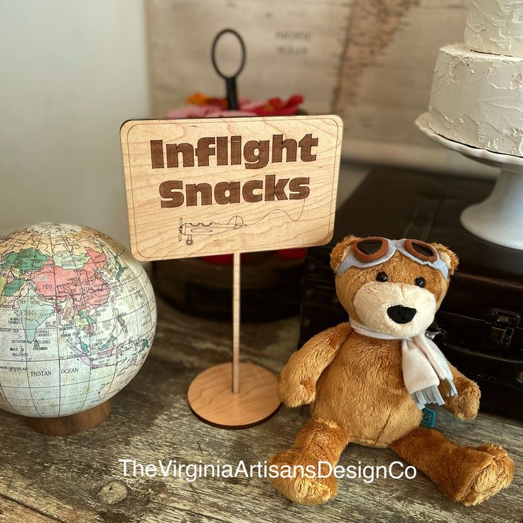 a teddy bear sitting next to a sign that says inflightt snacks on it