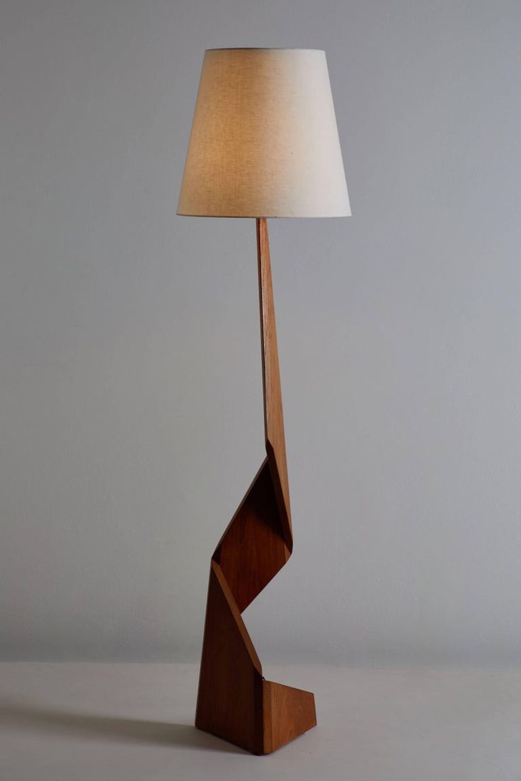 a wooden table lamp with a white shade on the top and bottom part of it