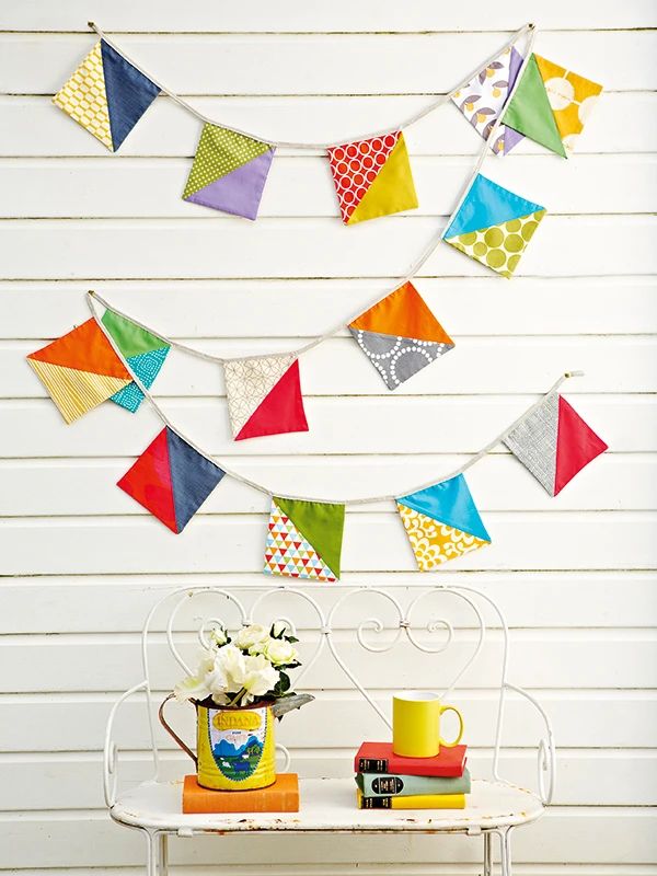 a table topped with a white bench covered in colorful kites hanging from the ceiling