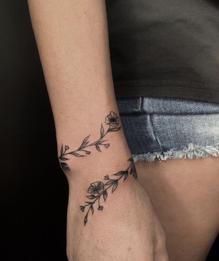 a woman's arm with a flower tattoo on the left side of her wrist