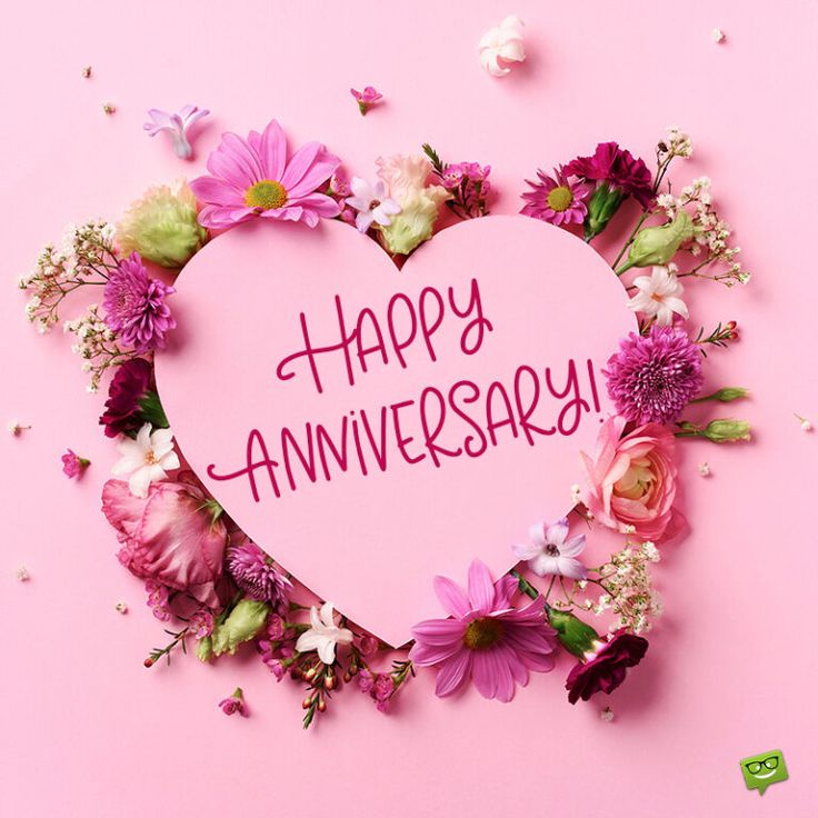 a pink heart with the words happy anniversary written on it surrounded by flowers and petals