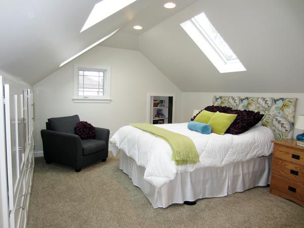 an attic bedroom with a bed, chair and window in it's center area