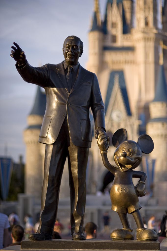 a statue of mickey and mickey mouse in front of a castle