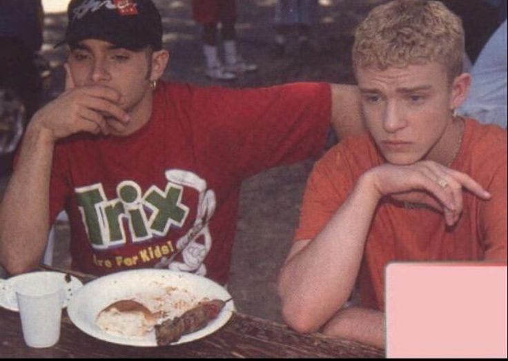 two young men sitting at a table with food