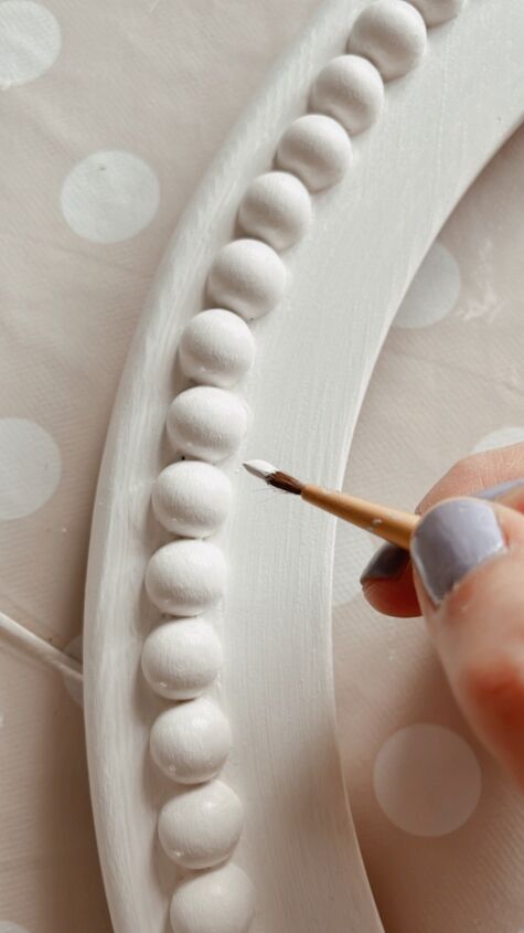 a person is holding a pencil and drawing something on a white plate with polka dots