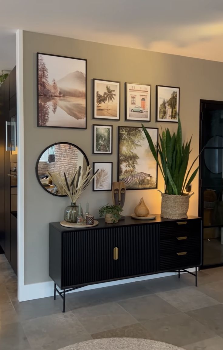 a living room with pictures on the wall and plants in vases next to it