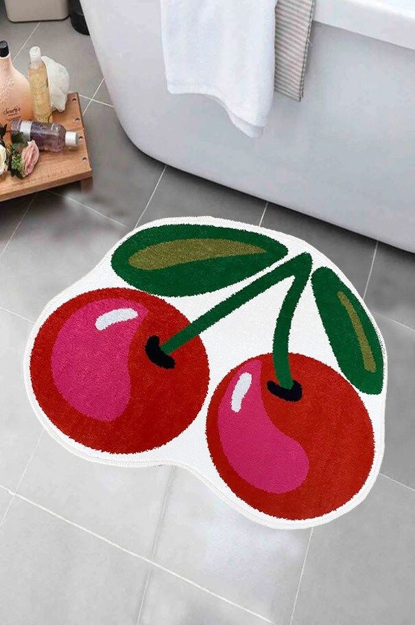 a bathroom rug with two cherries on it and a bathtub in the background