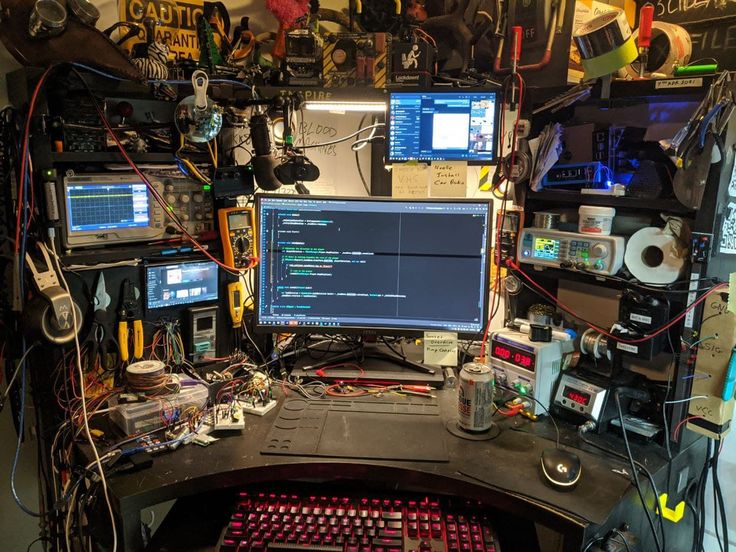 a computer desk with multiple monitors and other electronic equipment on it's sides, all covered in wires