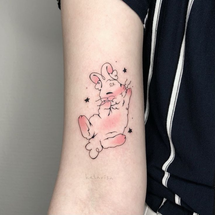 a woman's arm with a small tattoo of a pink teddy bear on it