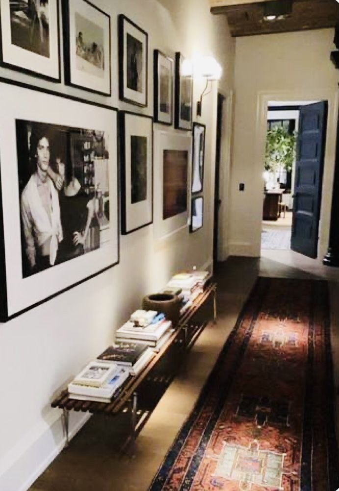 a hallway with pictures on the wall and a long rug in front of it,