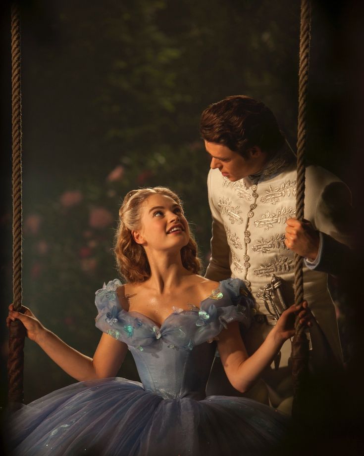 a man standing next to a woman in a blue dress on top of a swing