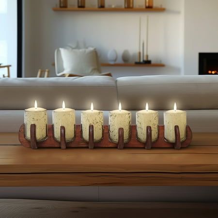 five candles are lit on a table in front of a couch and fireplace with the lights turned on