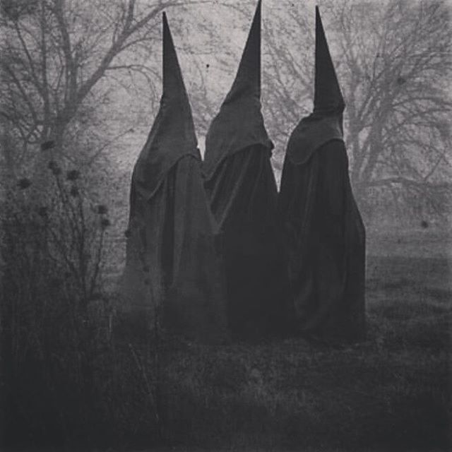 three witches standing in the woods with their heads turned to look like they are wearing black cloaks