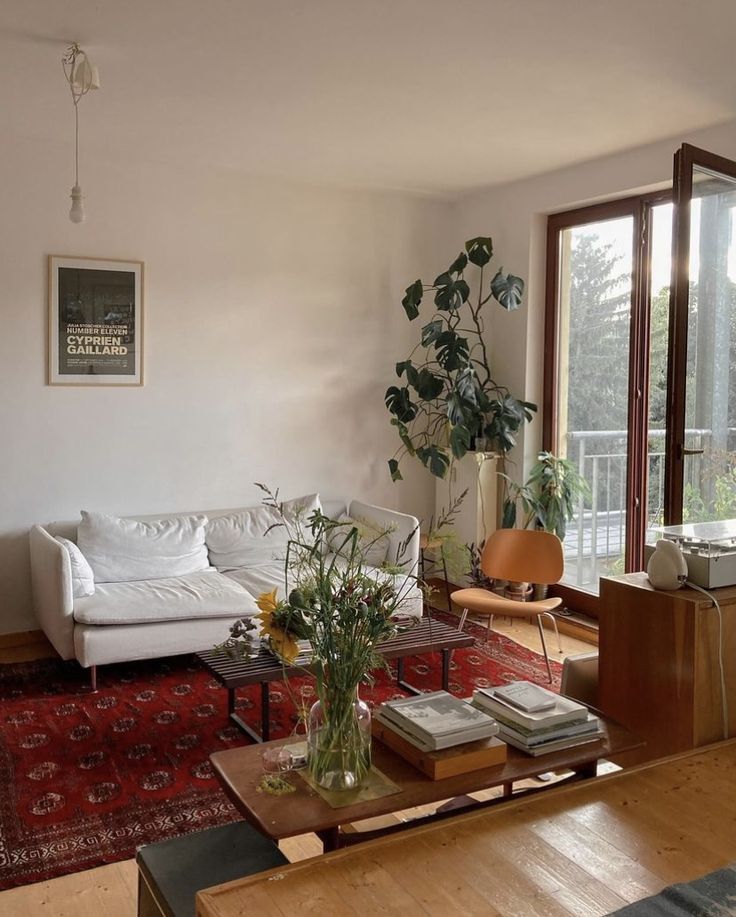 a living room filled with furniture and a red rug on top of a wooden floor