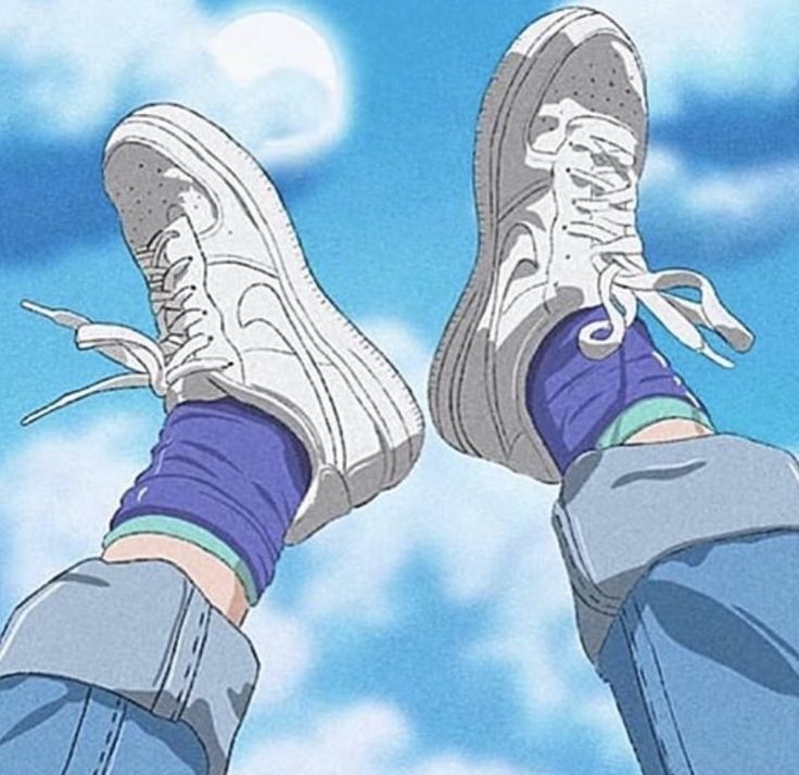 someone's feet with blue jeans and sneakers on, standing in front of the sky