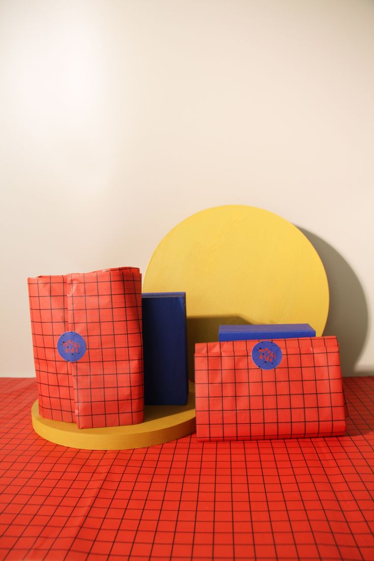 three bags sitting on top of a red table next to a yellow and blue object